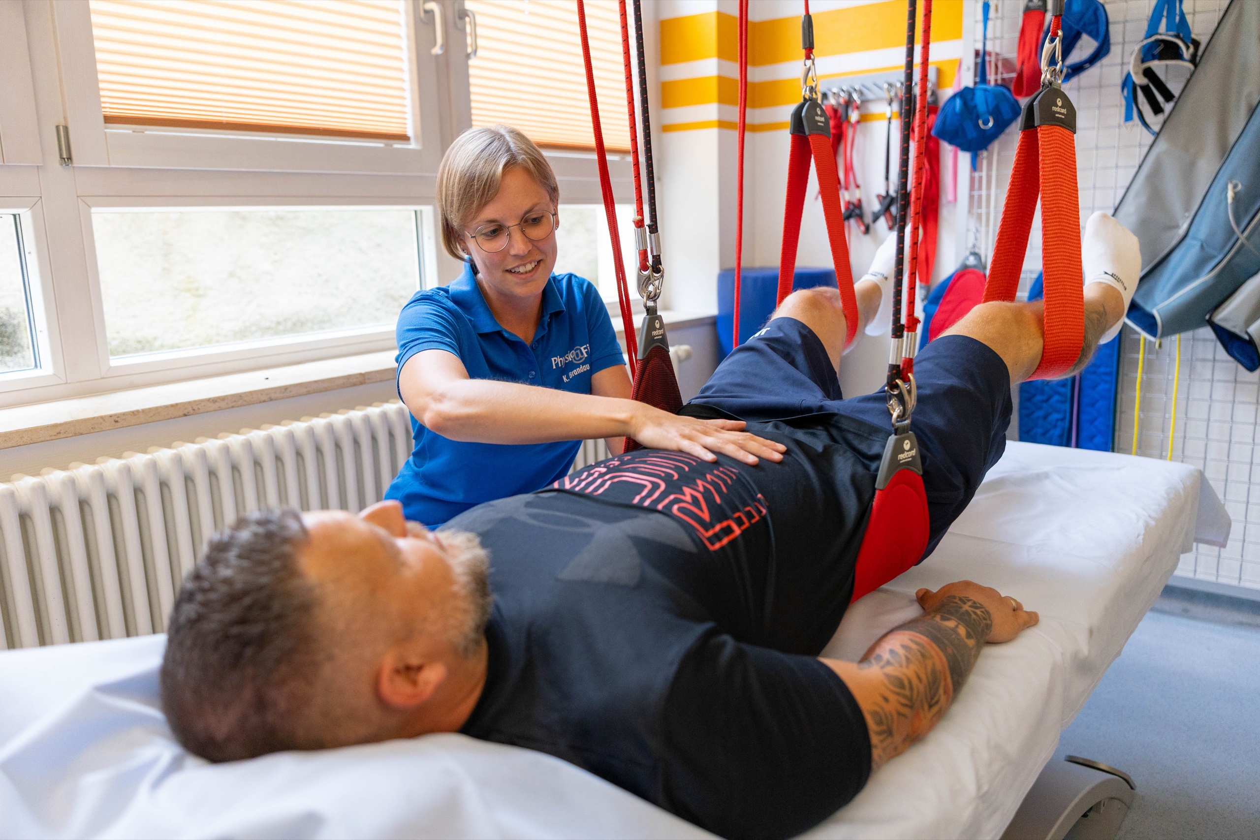 Physiotherapeutin bei einer Behandlung mit dem Redcord-Schlingensystem