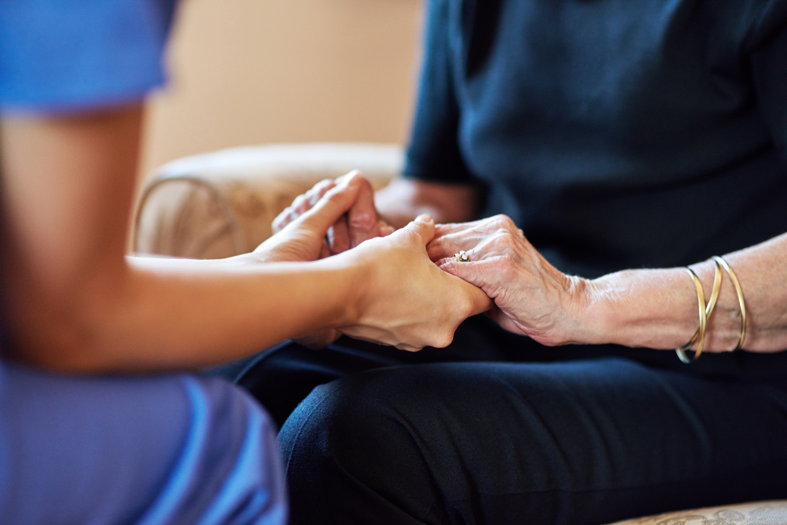 Pflegende Hände halten die Hände einer älteren Patientin